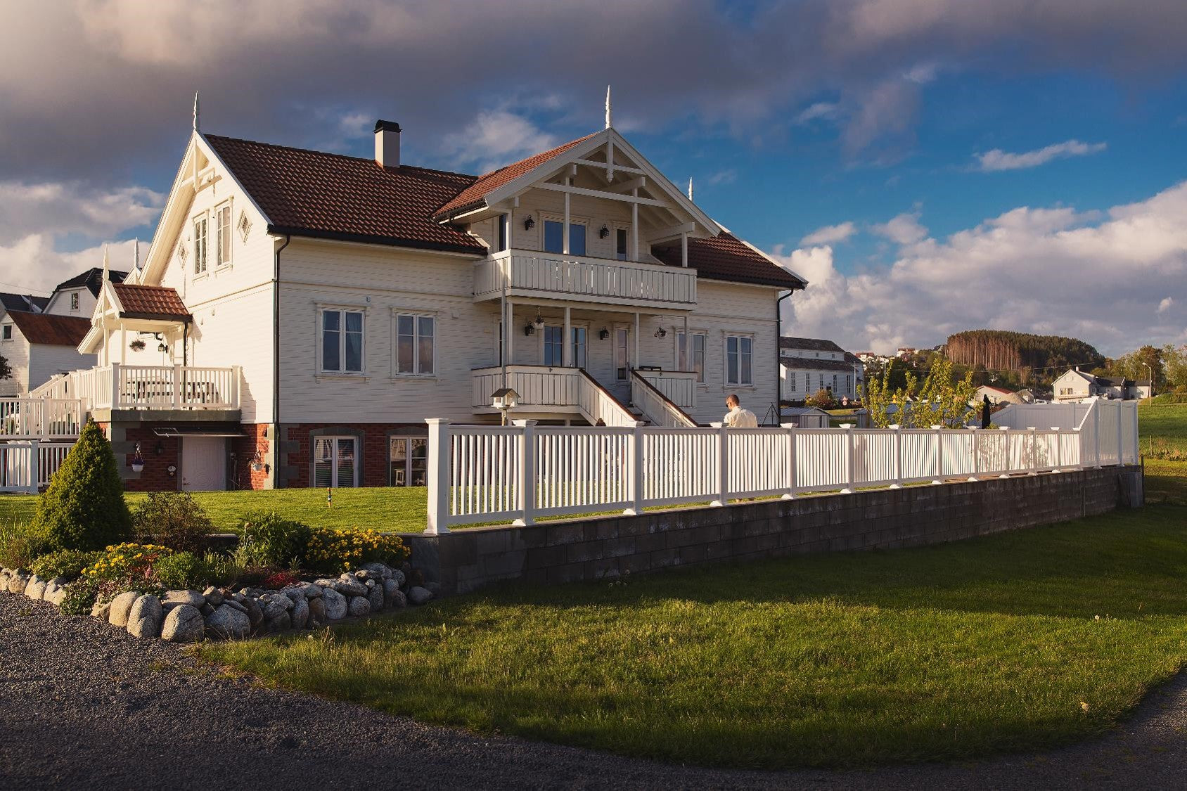 Hvitt PVC hagegjerde montert på mur foran et klassisk hus